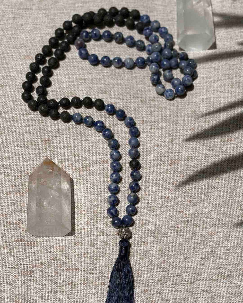 Meditation necklace with beads and tassel on a textured surface