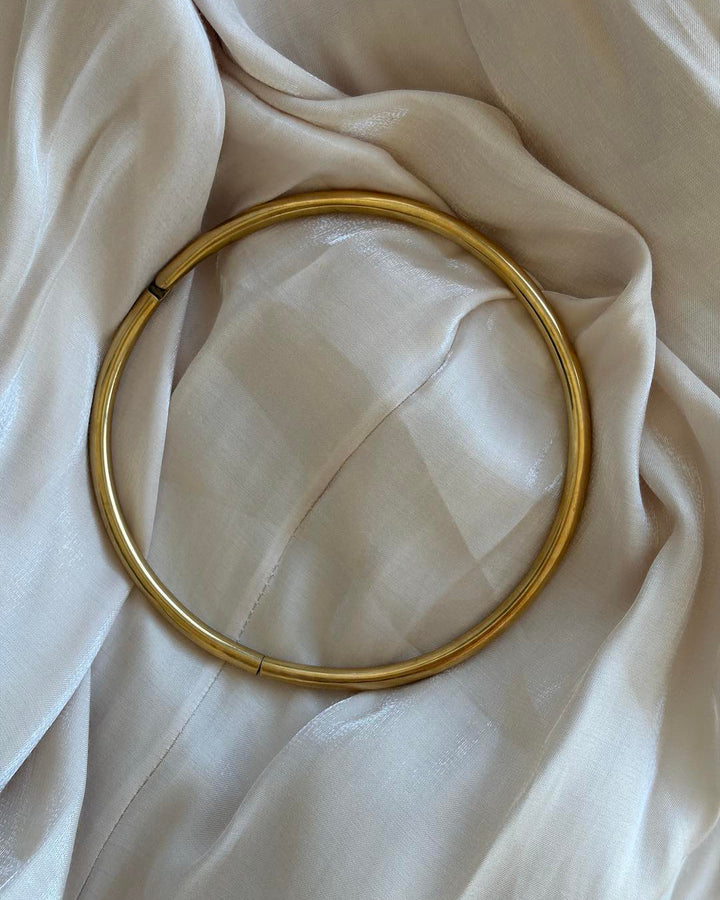 Gold hoop neck choker on a beige fabric background