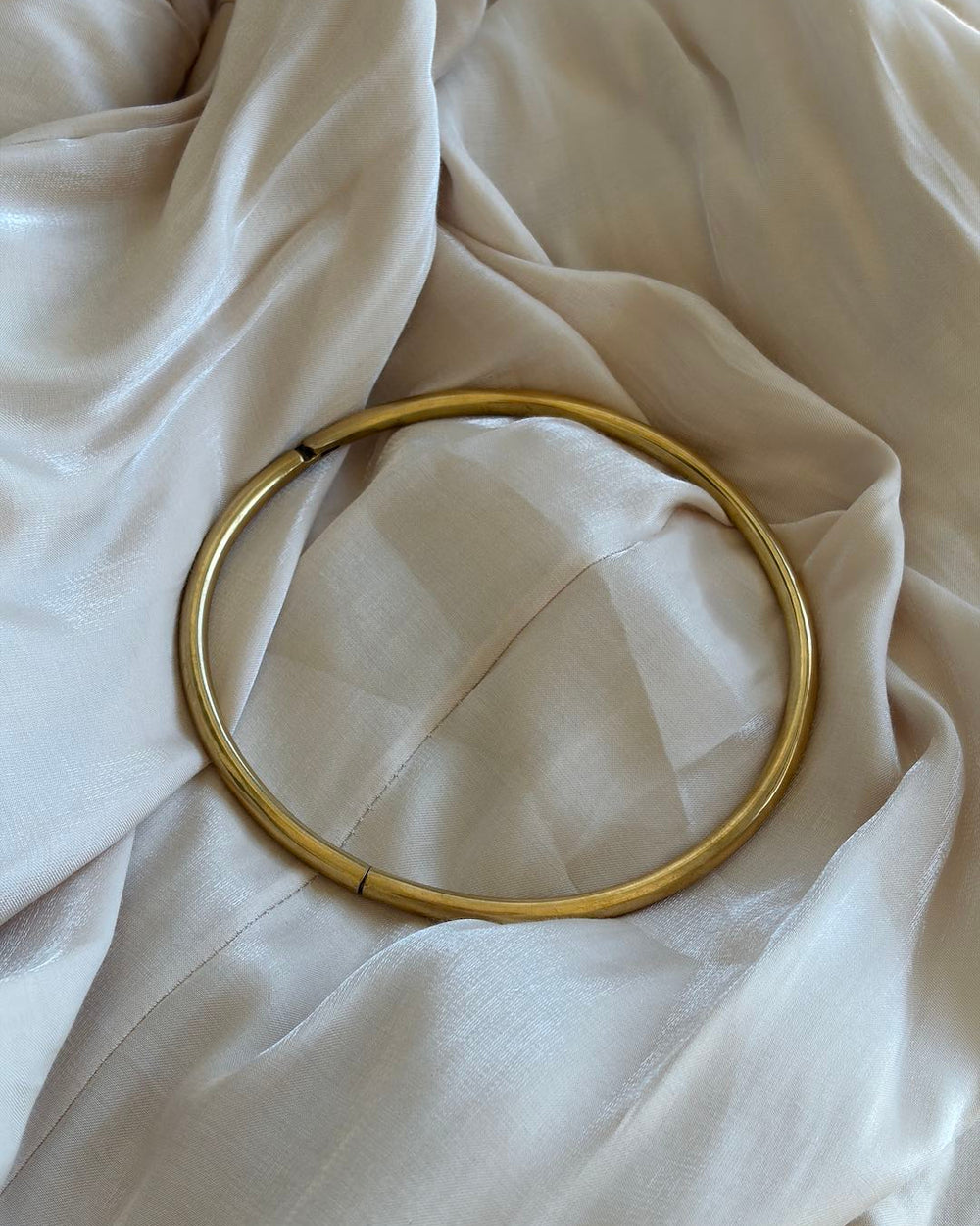 Gold hoop neck choker on a beige fabric background