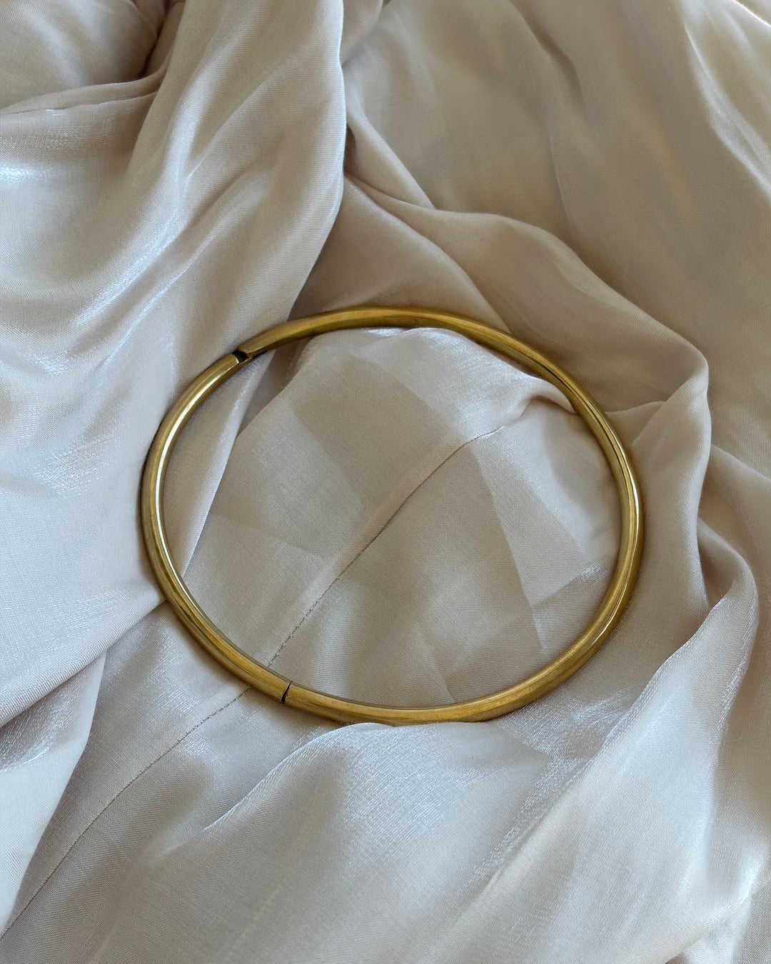Gold hoop neck choker on a beige fabric background