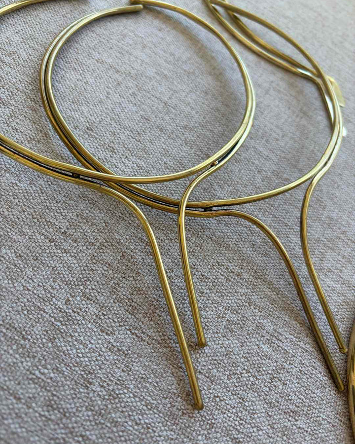 Gold metal neck chokers on a textured fabric background