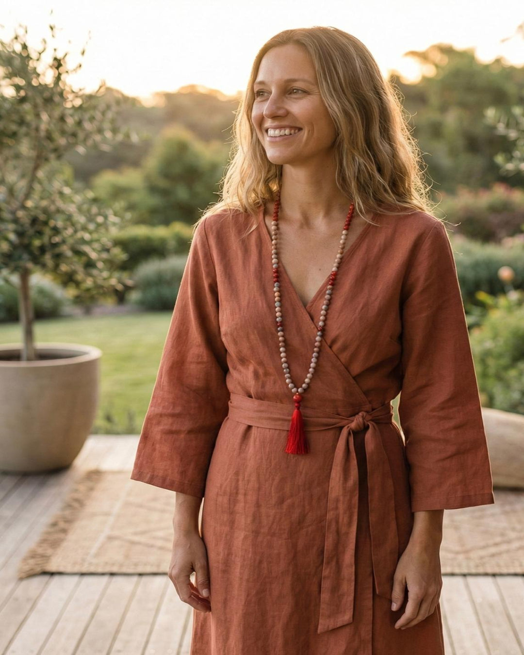 Woman in a rust-colored dress with a necklace standing outdoors.
