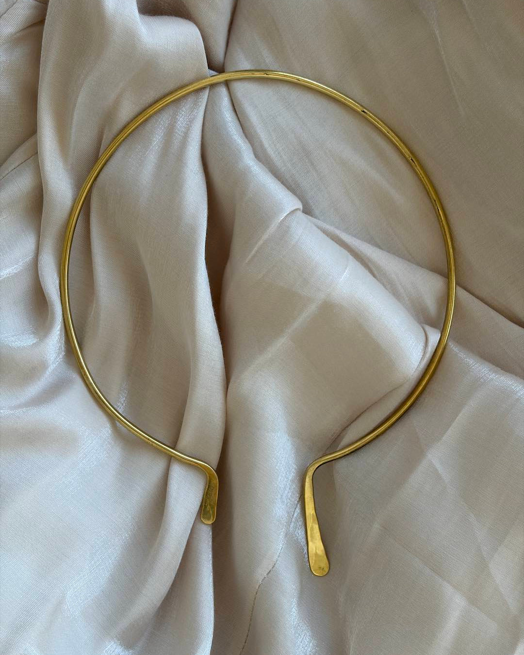 Gold neck band on a beige fabric background