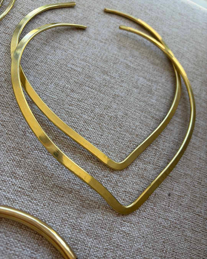 Gold hoop neck chokers on a textured beige surface