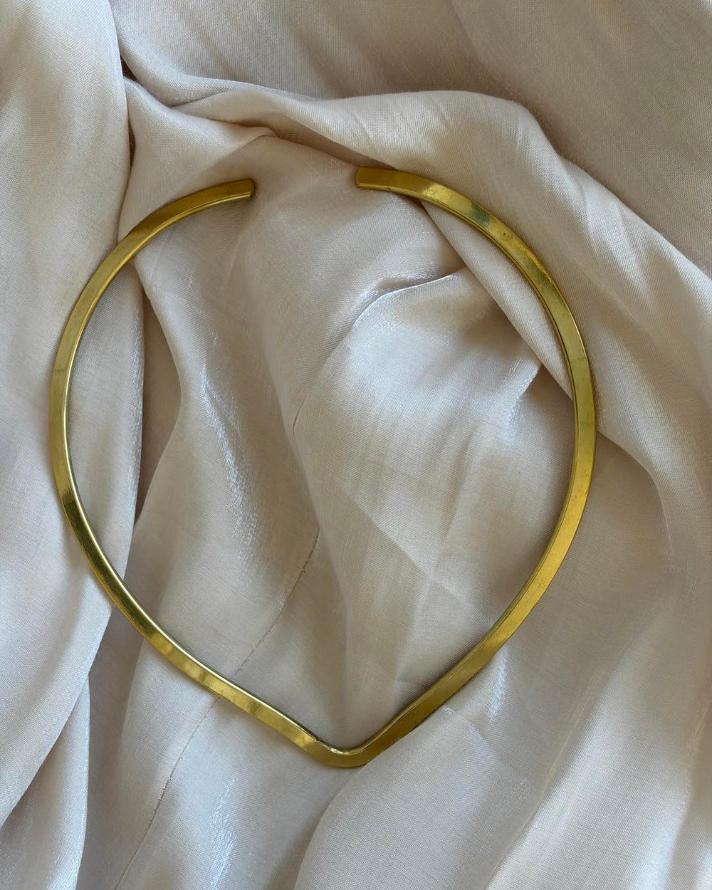 Gold choker on a soft beige fabric background