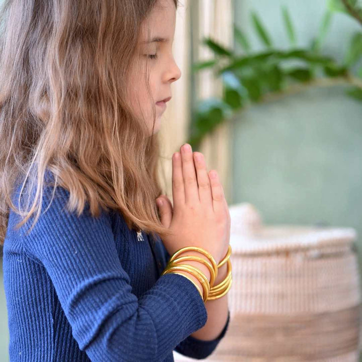 A girl wearing the Original Gold Leaf Temple Bangles with Mantra Kids Edition