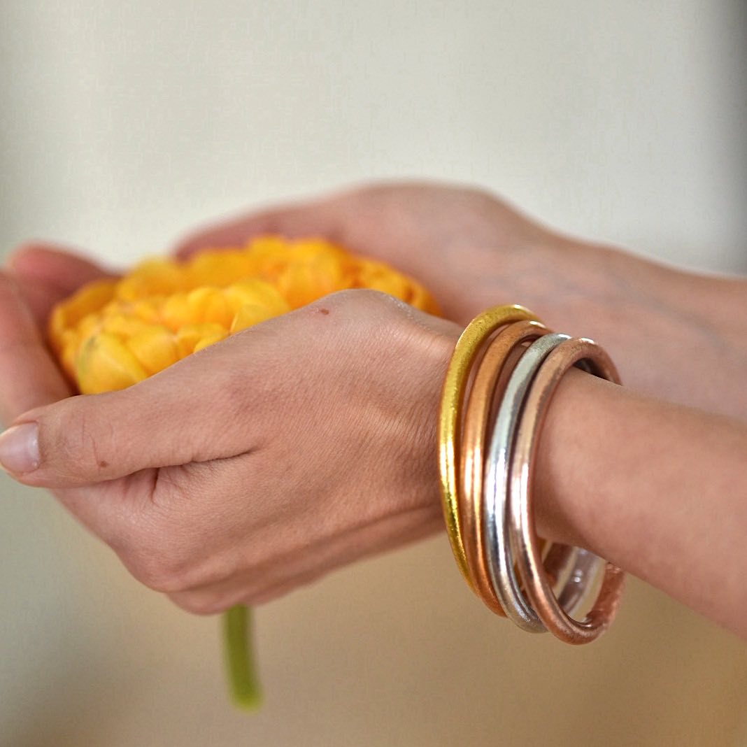 lady wearing a 4 stack of buddha gold leaf temple bangles with mantra